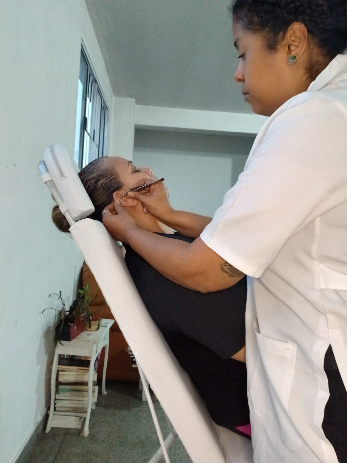Georgea aplicando um ponto na orelha da paciente com uma pinça