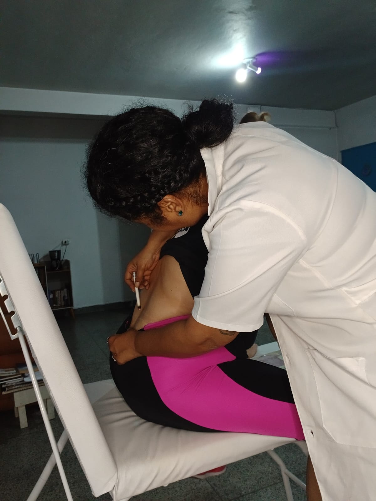 Georgea aproximando o bastão de moxa das costas da paciente